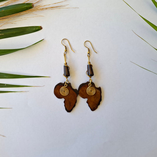 Pair of wooden earrings with gold accents on a white background with green leaves.