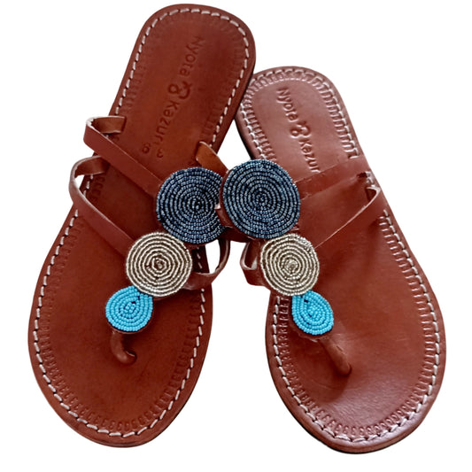 Brown sandals with decorative blue and gold elements on a white background